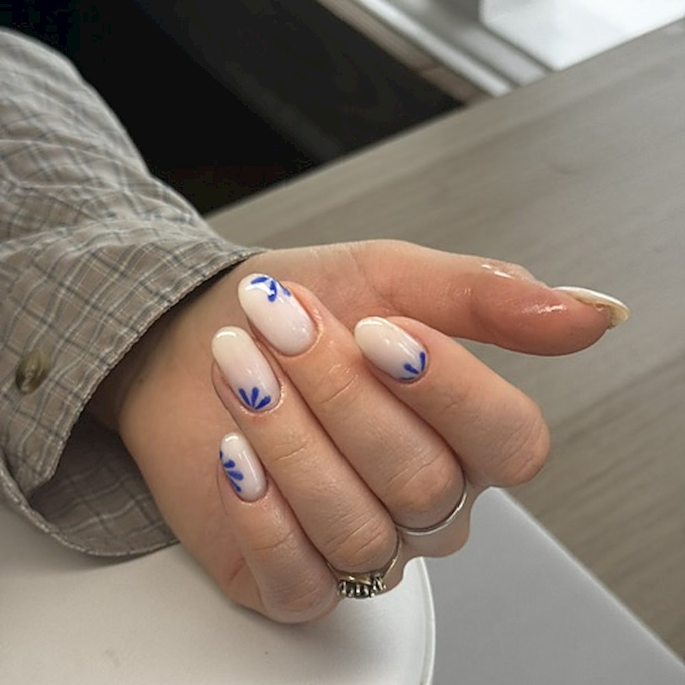 Nude nagels met handgeschilderde kobaltblauwe blaadjes