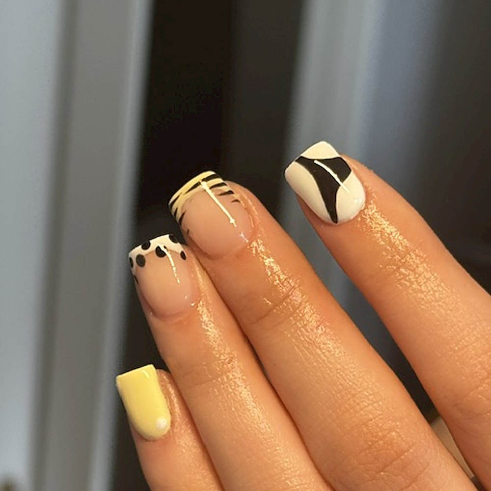 Vierkant gevijlde nagels in zachtgeel met zwart-witte nagelart en gouden lijnen